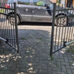 Geöffnetes zweiflügeliges Einfahrtstor mit neuem elektrischem Torantrieb vor einem PKW in Potsdam.