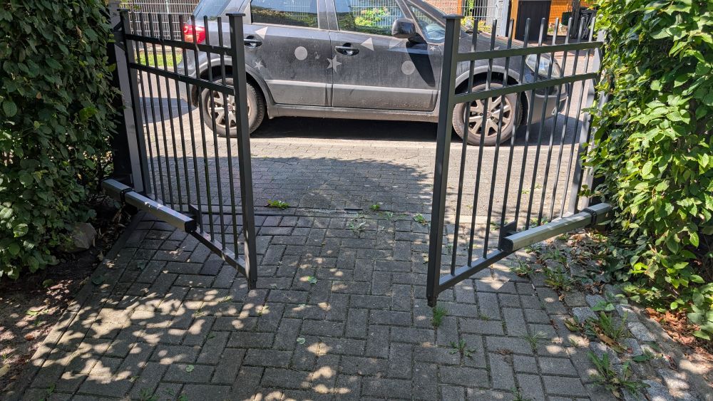 Geöffnetes zweiflügeliges Einfahrtstor mit neuem elektrischem Torantrieb vor einem PKW in Potsdam.